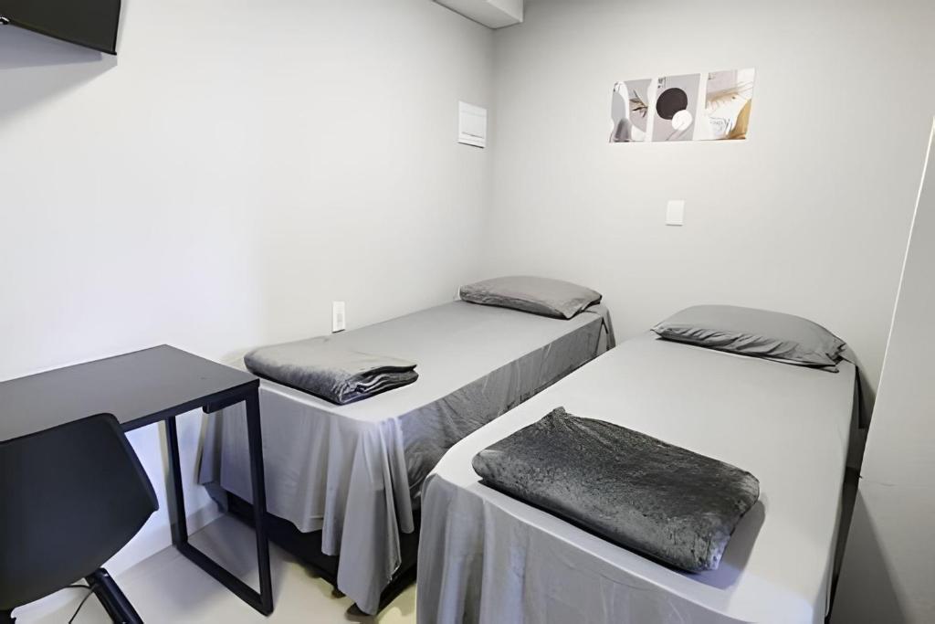 two beds in a room with a table and a desk at Studio IX - Com Ar Condicionado - Jundiaí in Jundiaí