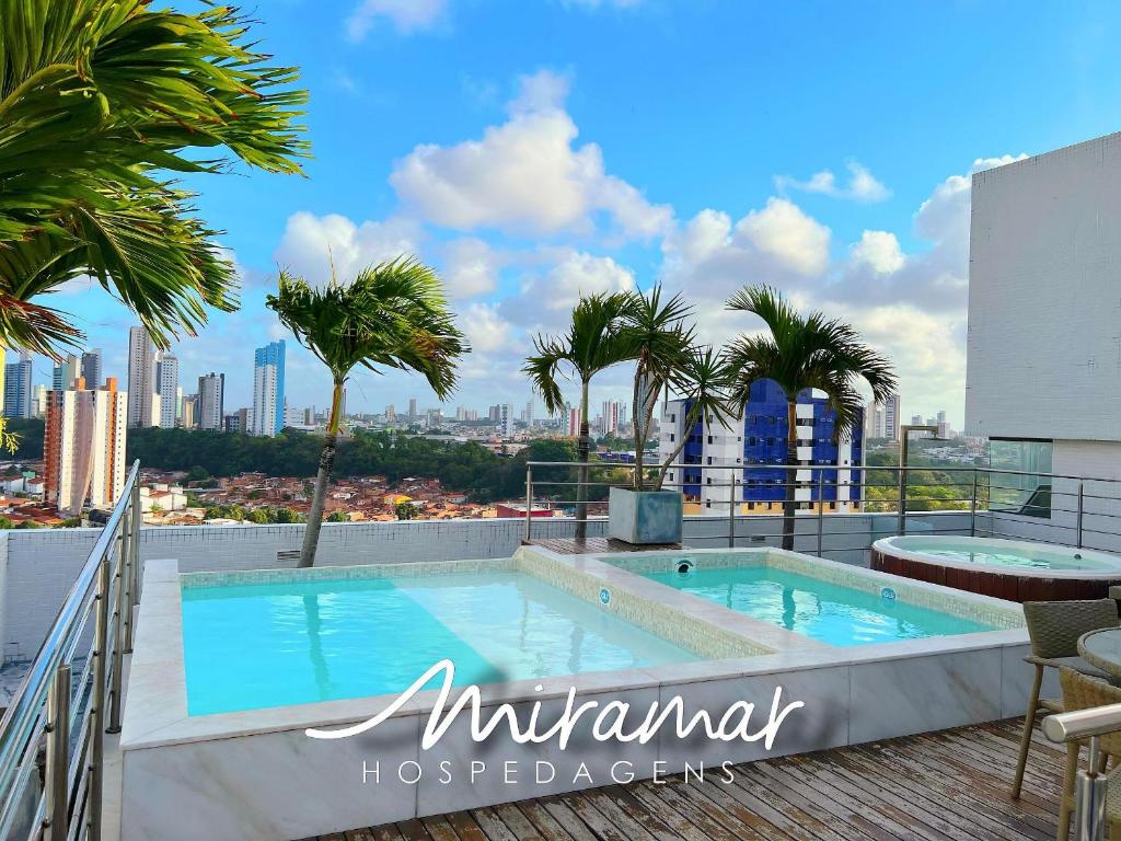 a swimming pool on the roof of a building with palm trees at Lindo flat no Manaíra Apart Hotel in João Pessoa