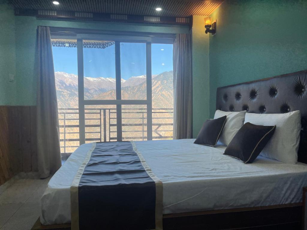 a bedroom with a large bed with a view of mountains at Laxman Homestay in Sarāhan