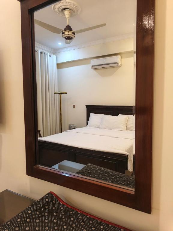 a mirror reflecting a bed in a room at The Aristocrat Residency in Islamabad