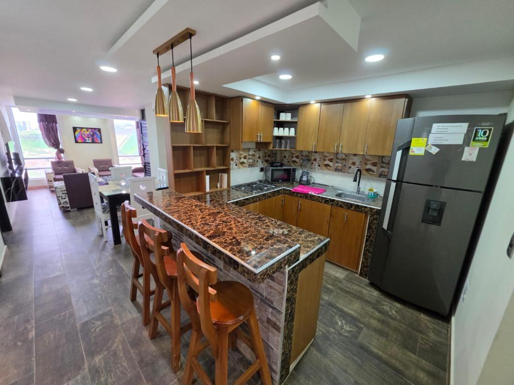 a kitchen with a counter with chairs and a refrigerator at Torres buambiles 2 in Ipiales