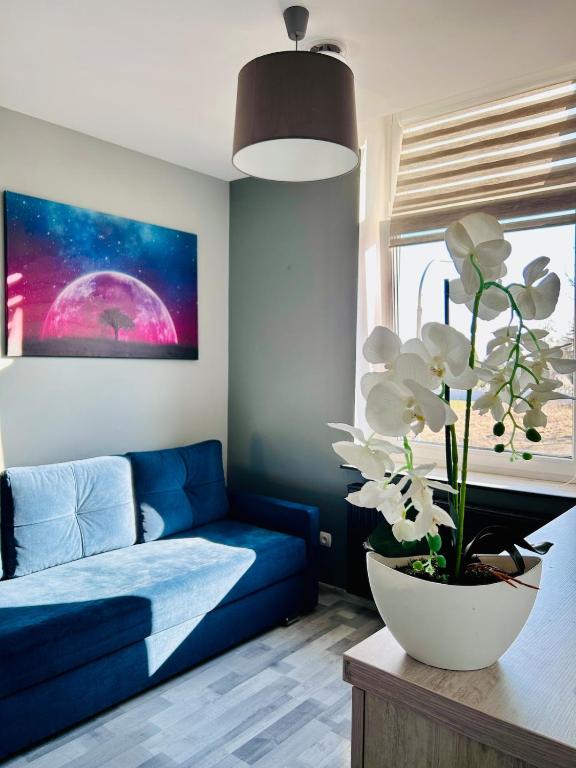 a living room with a blue couch and a vase with white flowers at Chopina Place in Oświęcim