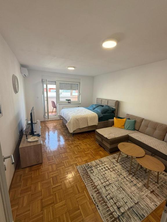 a living room with a bed and a couch at MAAA Apartman in Tuzla