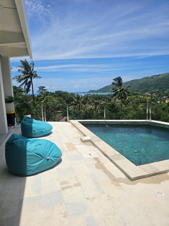 a swimming pool with two blue bean bags next to it at Tris Villas ocean view in Kuta Lombok