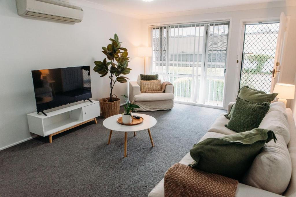 a living room with a couch and a tv and a table at The Retreat on Piper in Tamworth