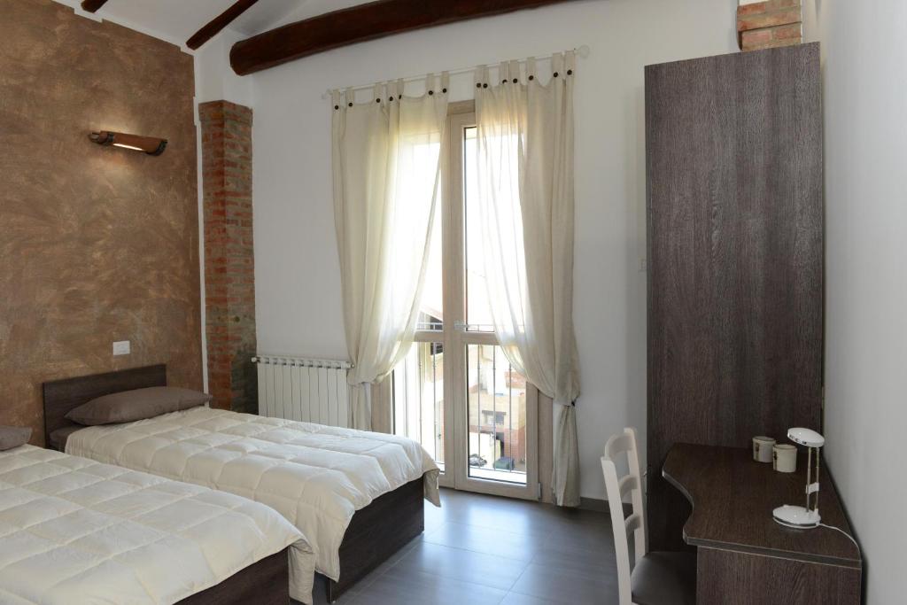 a bedroom with two beds and a table and a window at il leccio in San Lazzaro di Savena