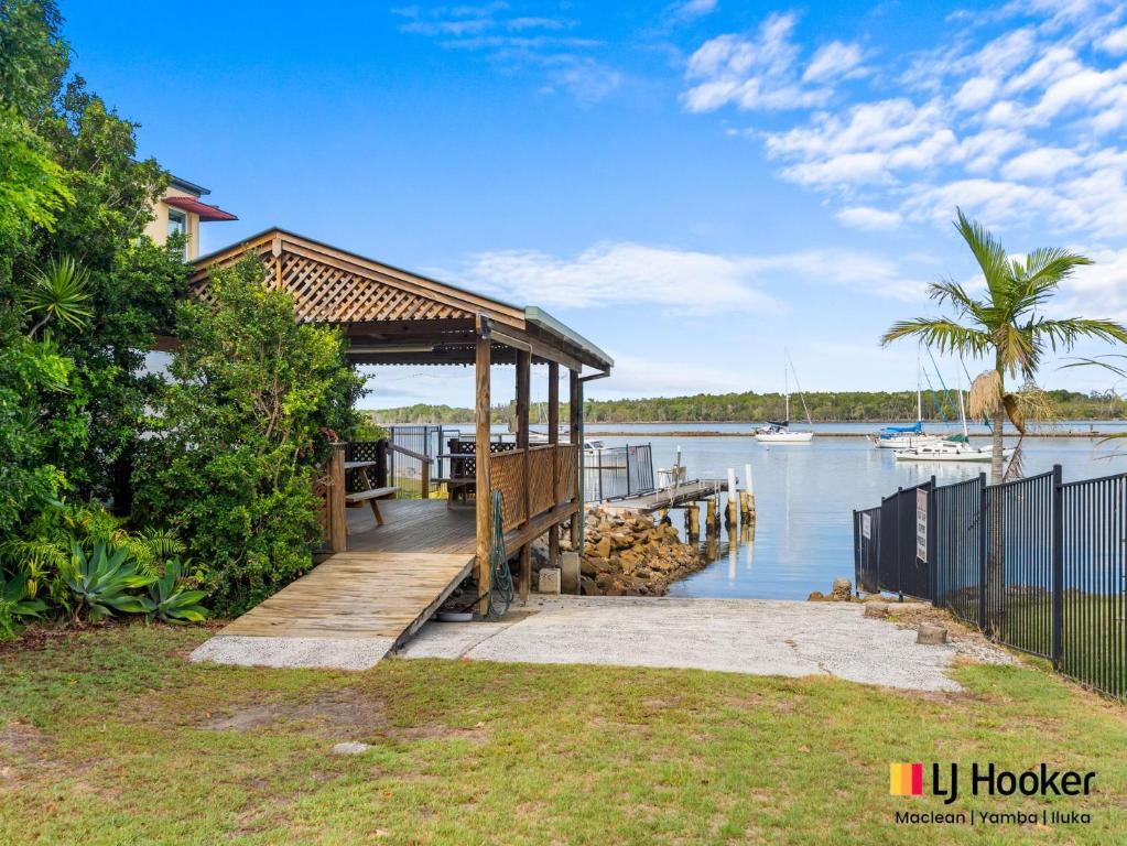 a house with a wooden dock next to a body of water at Iluka Villa 2 in Iluka