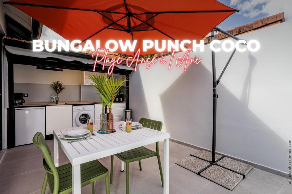 a dining room with a white table and an umbrella at Bungalow PunchCoco - Beachfront in Les Trois-Îlets
