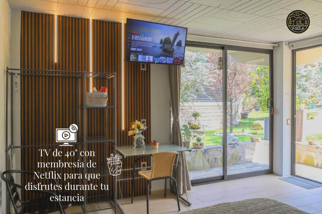 a room with a table and a tv on the wall at ValZur Hospedaje-Habitación Acacias in Villa del Carbón