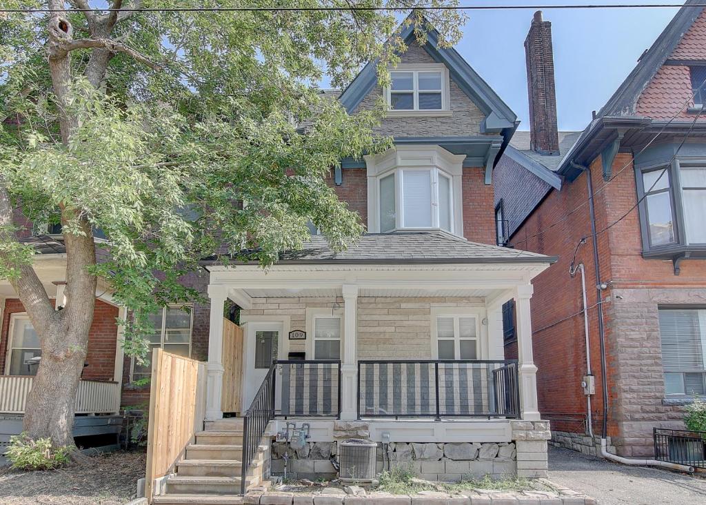 a house with a porch and stairs in front of it at Spadina Boutique Rooms in Toronto