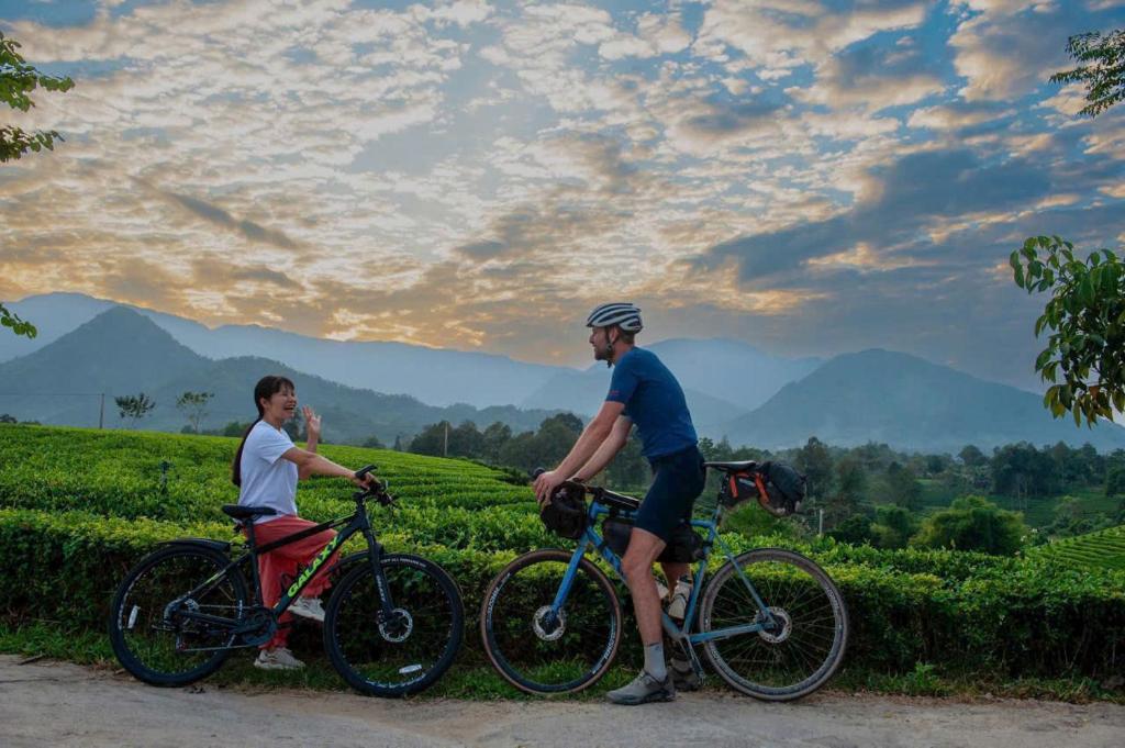 two men riding bikes in front of a tea plantation at Framstay Mây Sườn Đông in Ðại Từ