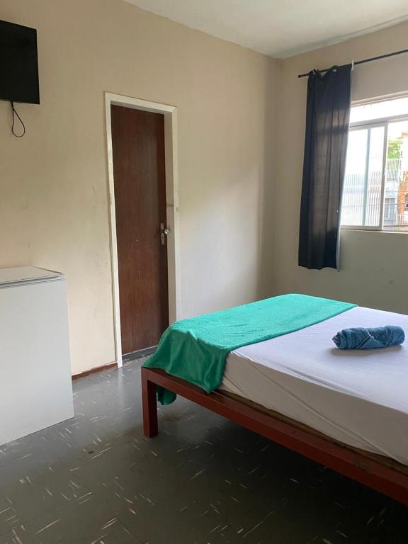 a bedroom with a bed and a window and a television at Quarto no centro in Sete Lagoas