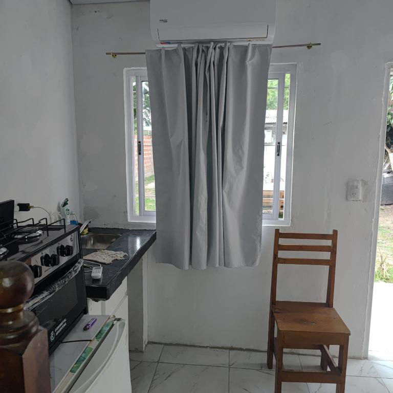 a kitchen with a window with a gray curtain at Hospedaje El Colibri in Ezeiza