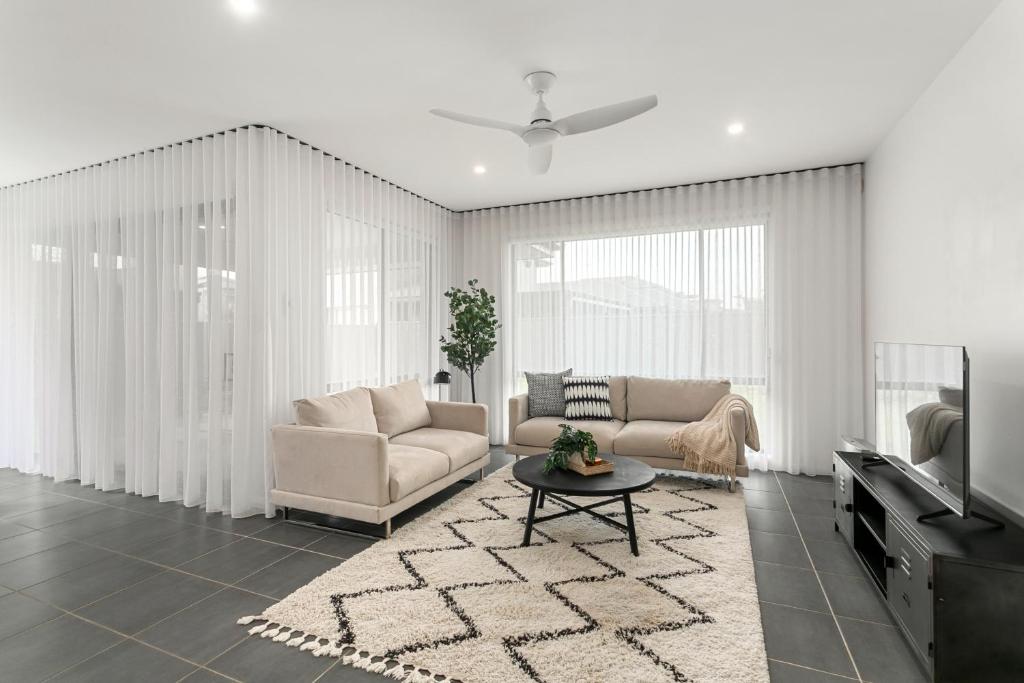 a living room with a couch and a tv at The Lavender House in Gledswood Hills