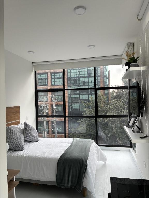 a bedroom with a bed and a large window at Modern studio apartment Parque de la 93 in Bogotá