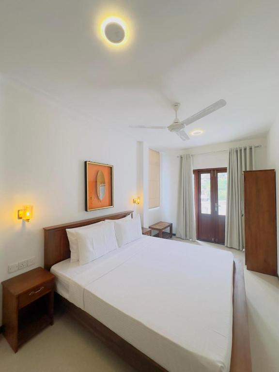 a bedroom with a large white bed and a window at abbbbn in Tennekumbura