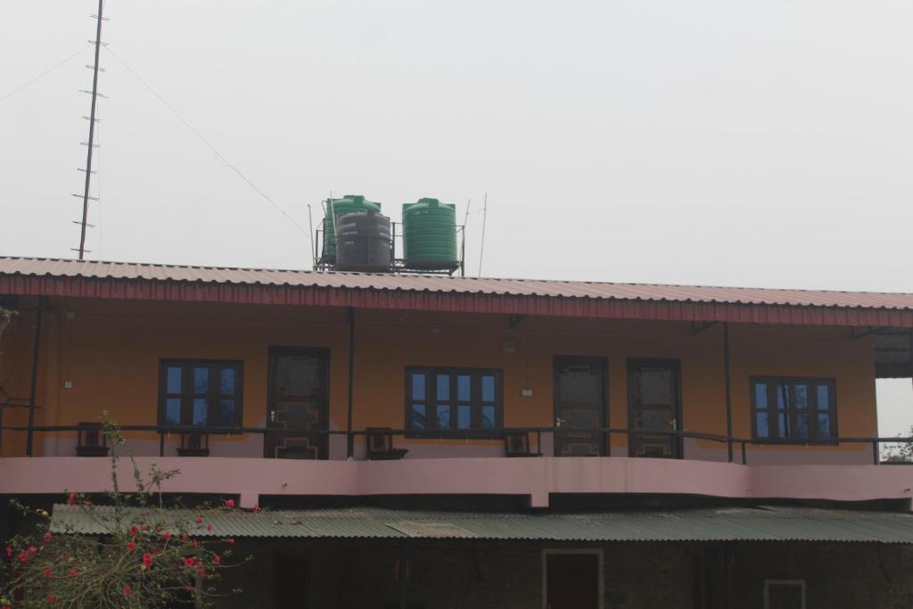 a building with a balcony with windows and a roof at Shanta Ghar A Rustic Guesthouse in Chitwan