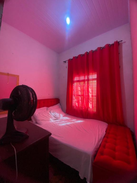 a bedroom with a bed with a red curtain at Quarto para temporada in Goiânia