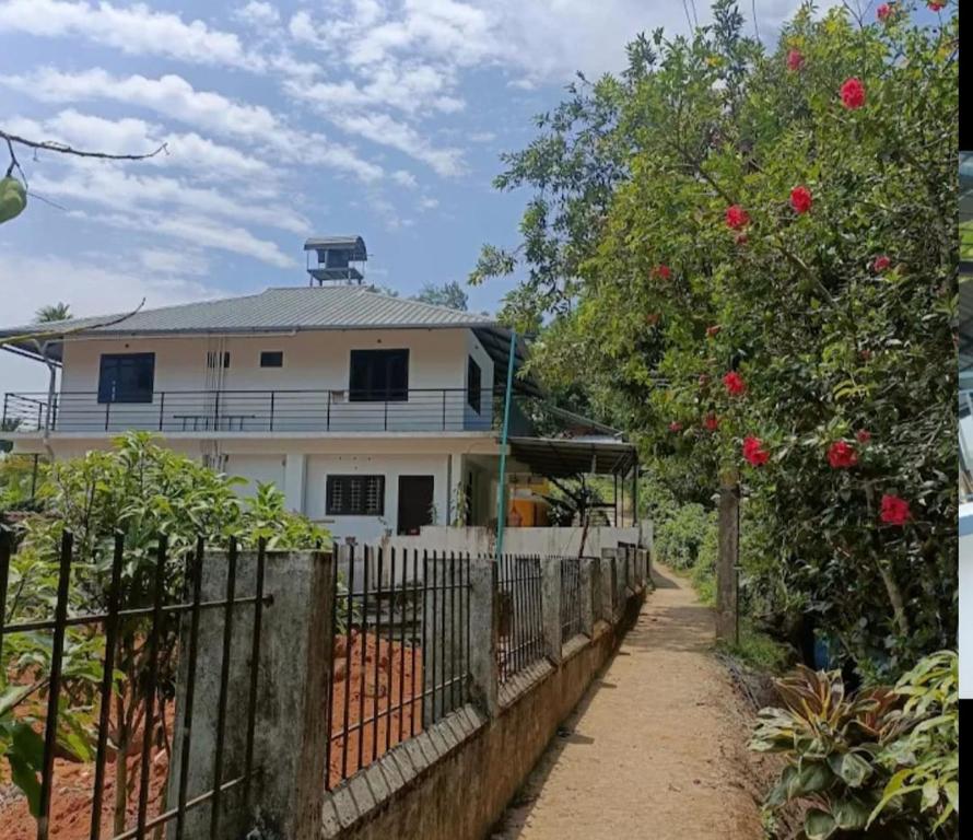a white house with a fence in front of it at Green Lounge in Munnar
