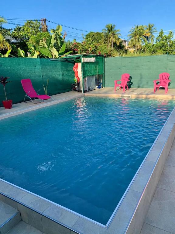 a swimming pool with two pink chairs and a swimming pool at Maison charmante à Petit-Bourg avec piscine partagée in Petit-Bourg