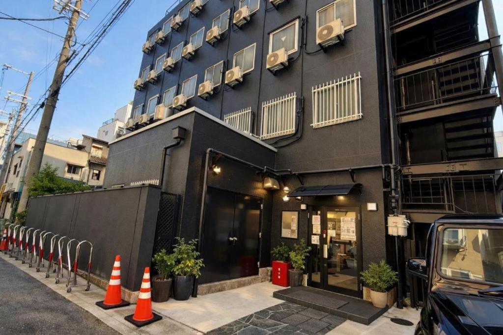 a black building with orange cones in front of it at 心斎橋難波関空直通Kumano Sanctum Ambers Hostel in Osaka