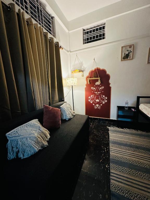 ein Wohnzimmer mit schwarzem Sofa und Vorhängen in der Unterkunft Nimo Homes in Kāziranga