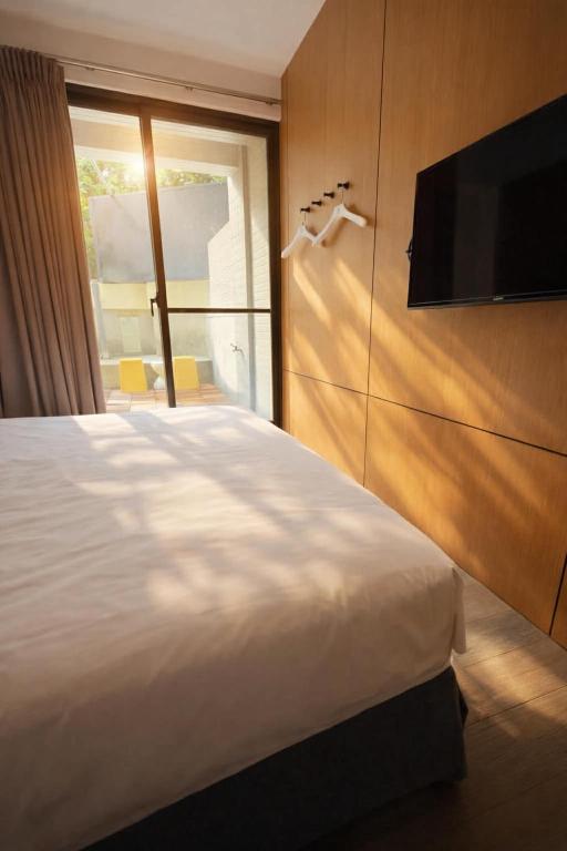 a bedroom with a bed and a flat screen tv at 逢甲25行館Fengjia 25 Hotel in Taichung