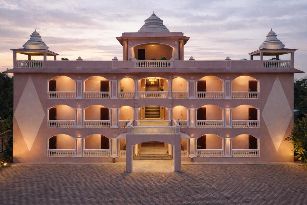 a large white building with a sunset in the background at Gangabagh by Divine Trails - Hotel Near Har Ki Pauri, Haridwar in Haridwār