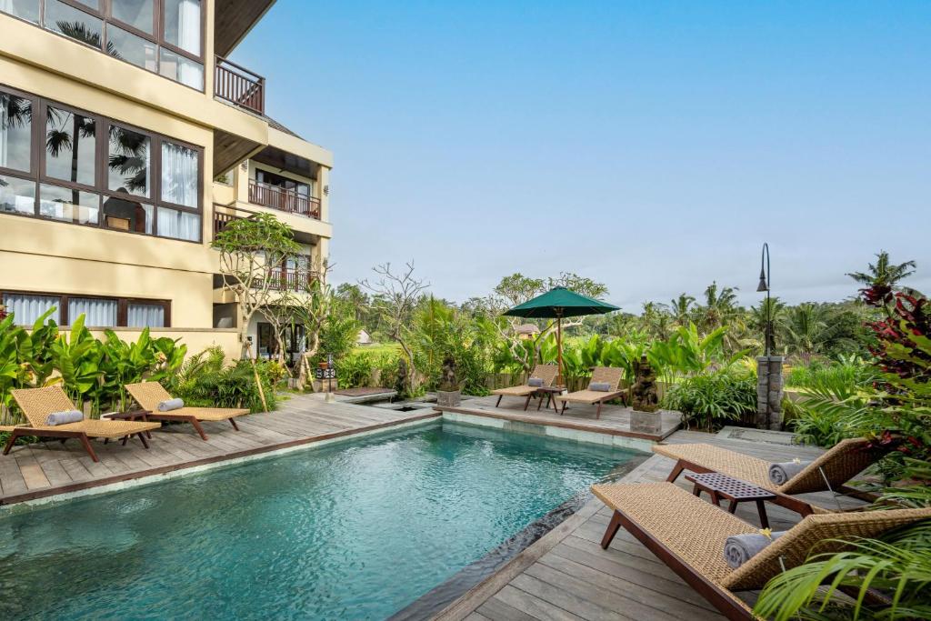 a swimming pool in front of a building at Emana Abian Taksu in Ubud