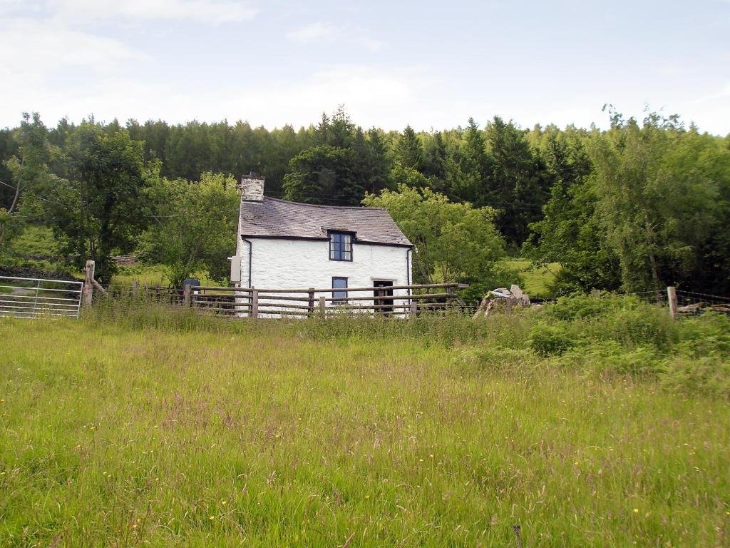 an old white house in the middle of a field at Crogen Bryn Awel in Llandrillo
