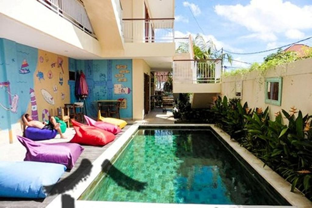 a swimming pool with chairs and a couch next to a house at Home 21 Bali in Sanur