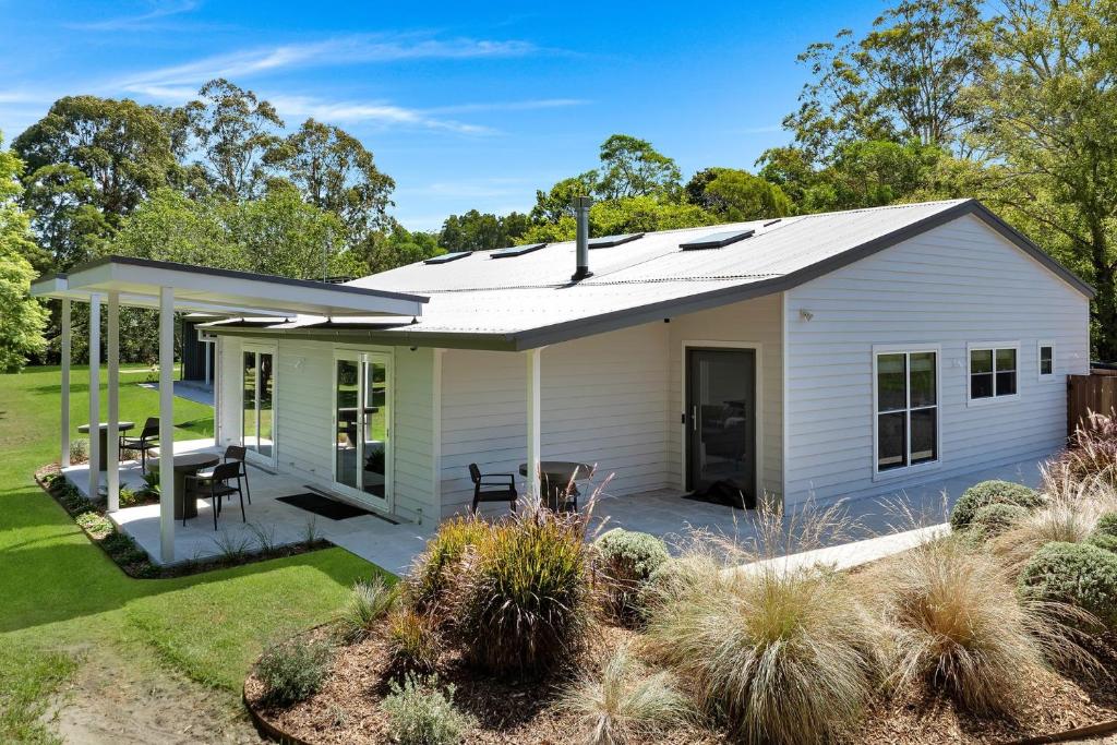 a white house with a patio and landscaping at Grovebrook Cottage, Broughton in Woodhill