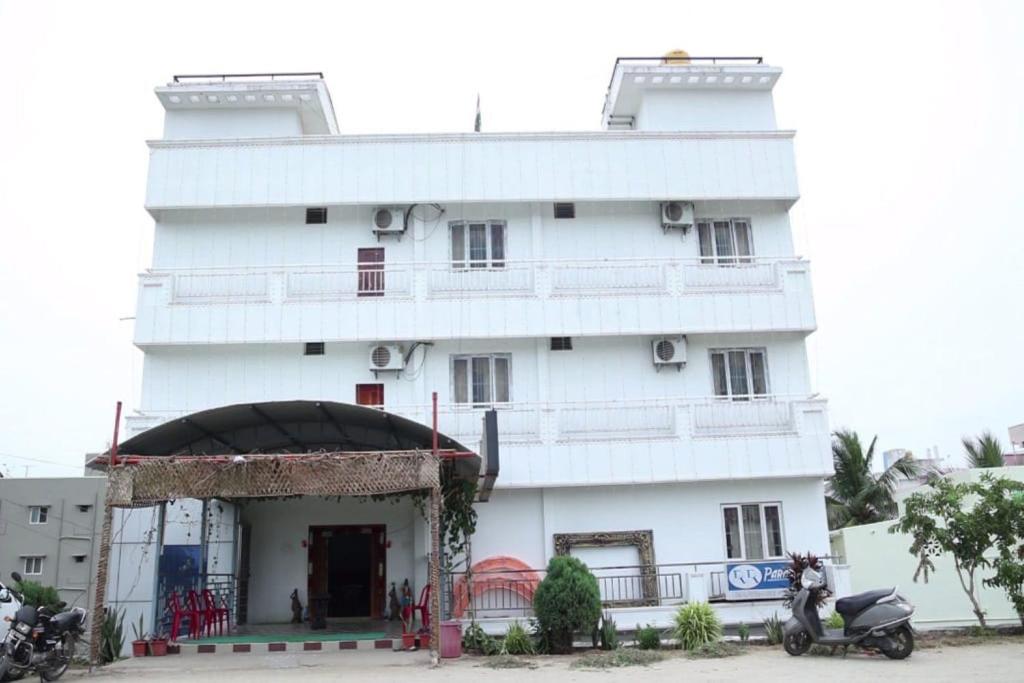 a white building with a scooter parked in front of it at R R Paradaise in Pūtalapattu