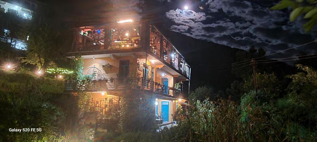 a lit up building with a balcony at night at White Rabbit Guest House in Dharamshala