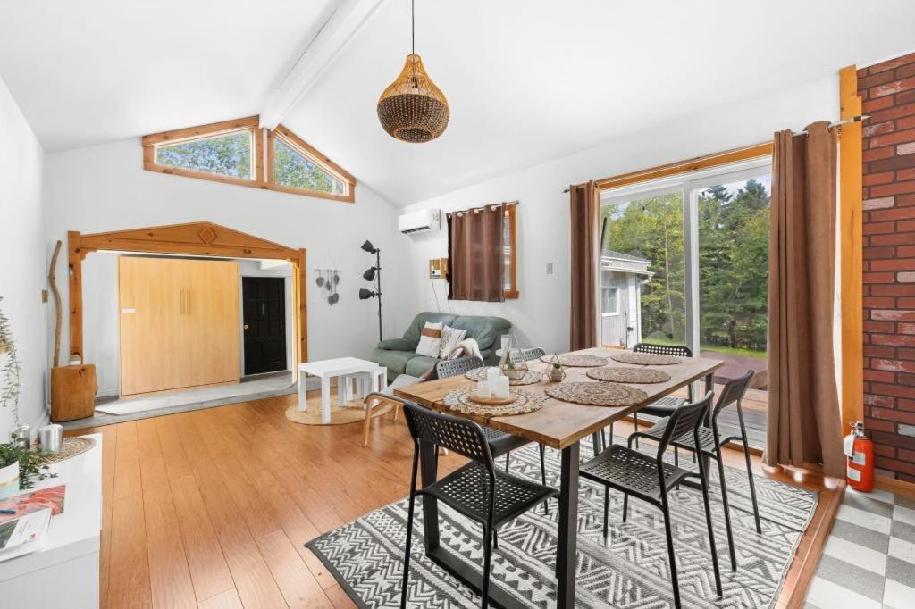 a living room with a wooden table and chairs at Spa - River & Forest View - Le Petit Cocon in Chateau Richer