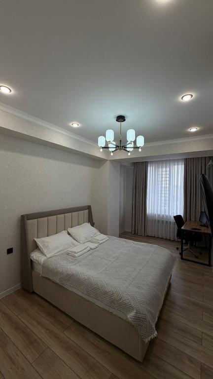 ein Schlafzimmer mit einem Bett und einem Kronleuchter in der Unterkunft Millennium in Bischkek