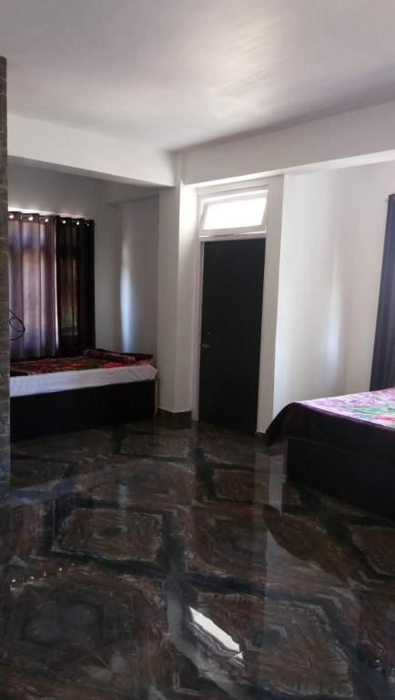 an empty room with two beds and a door at Hotel Aditya in Aritar