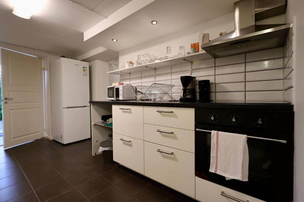 a kitchen with white cabinets and a black stove top oven at Workers Stay - Staff Apartment - Säve - Göteborg - Sverige in Säve