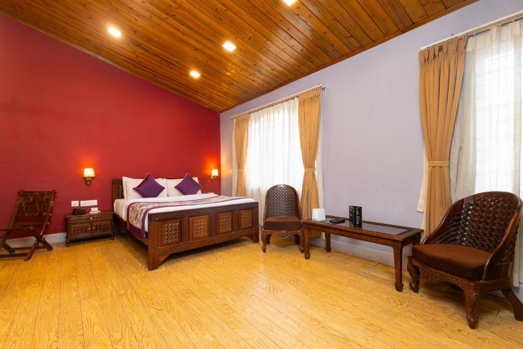 a bedroom with a bed and two chairs at Conifer Suites & Spa Darjeeling in Darjeeling