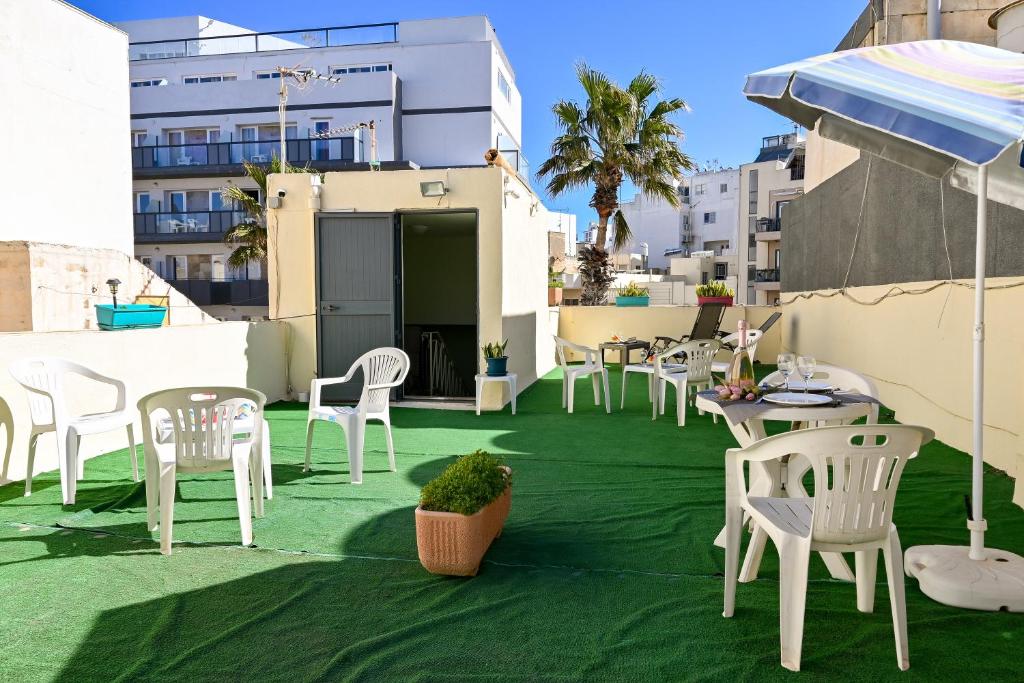 a patio with white chairs and tables on a roof at Sharon Court Guesthouse in St. Paul's Bay