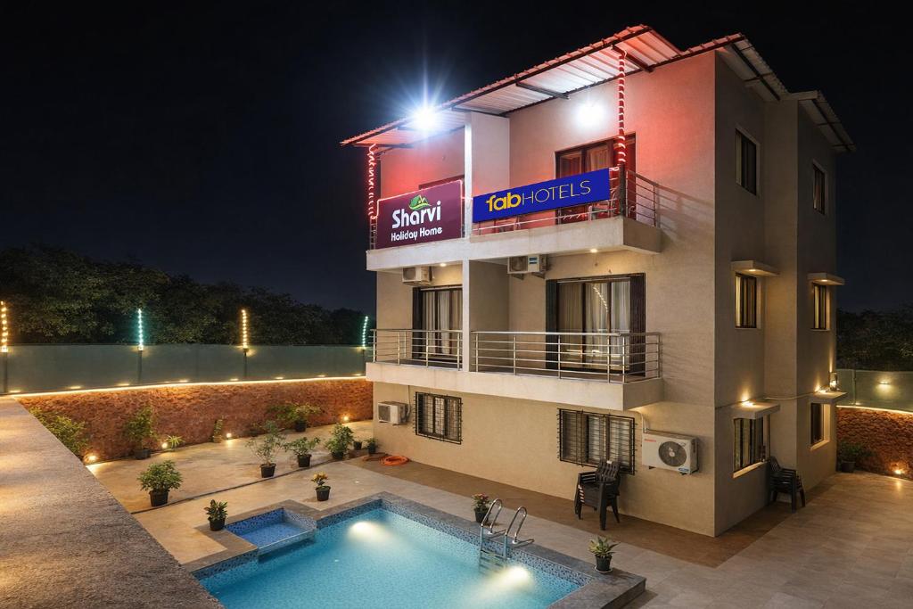 a hotel with a swimming pool in front of a building at FabHotel Sharvi in Mahabaleshwar