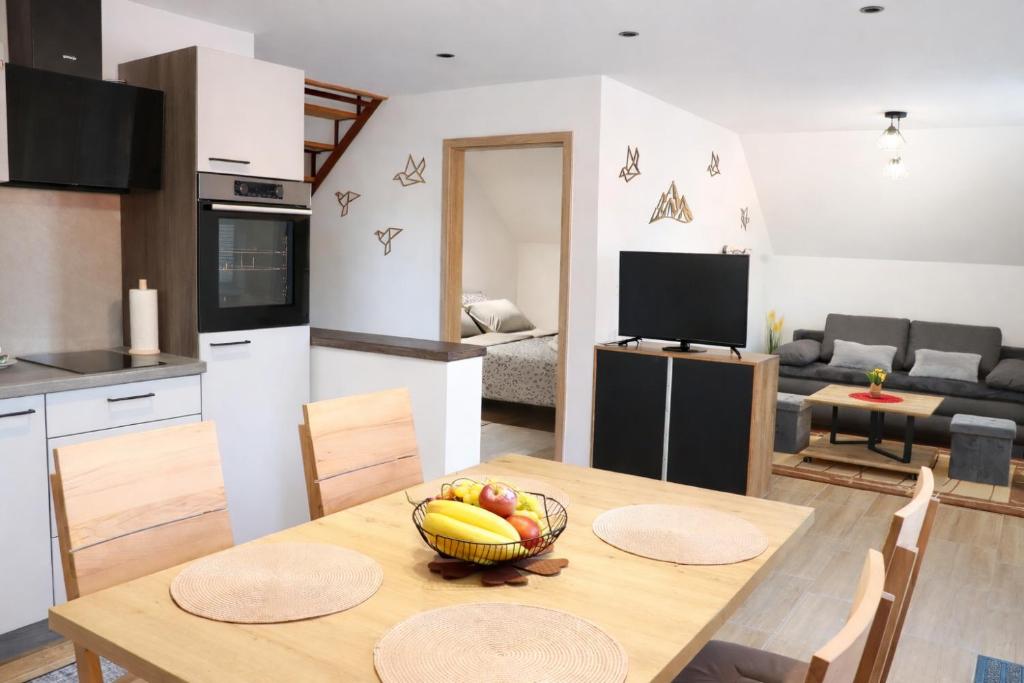 a kitchen and living room with a table with a bowl of fruit at Bled Castle View Apartment Medina in Zgornje Gorje