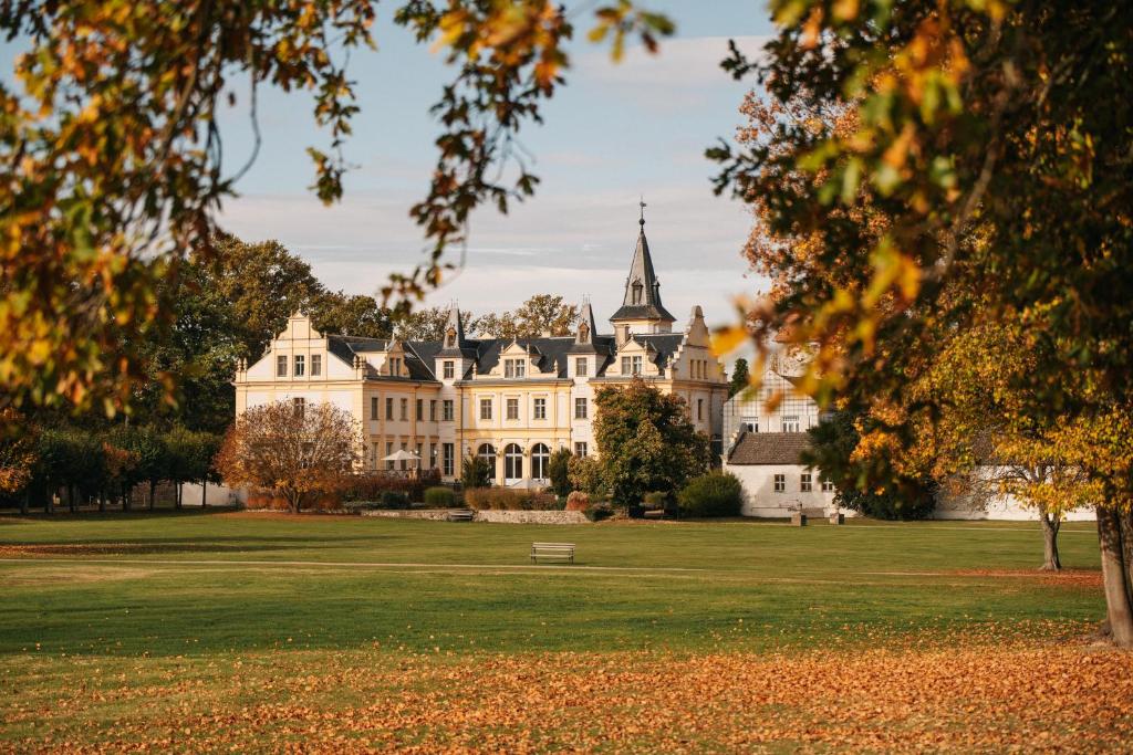 a large white mansion with a grassy field at Schloss und Gut Liebenberg in Liebenberg