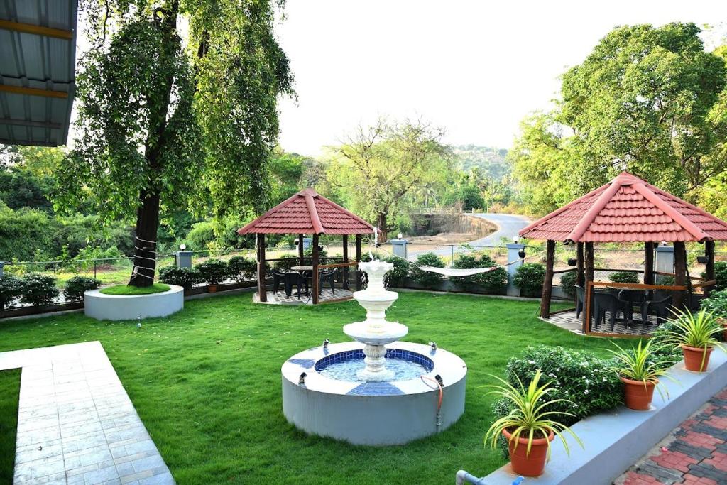 a fountain in the middle of a lawn with two gazebos at Hotel Akshada & Guest House in Banda