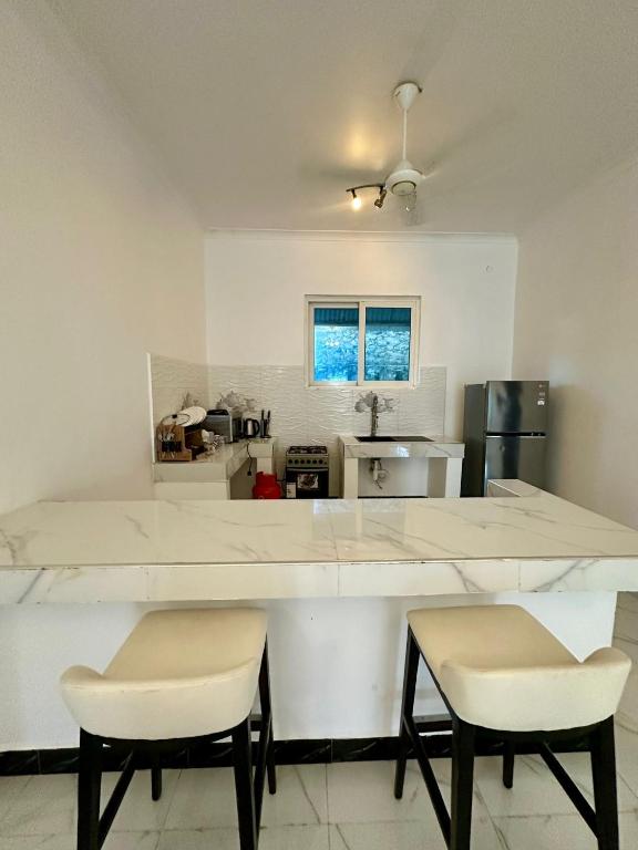 a kitchen with a large white counter and two chairs at Paje staycation apartment in Paje