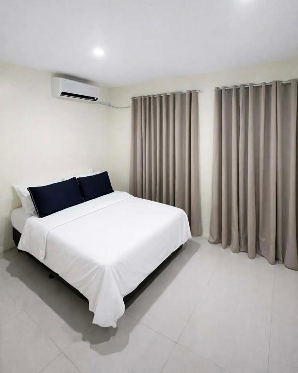 a white bedroom with a large white bed with blue pillows at Ben & Ben 2 in Cebu