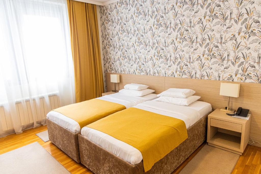 a bedroom with two beds with yellow and white sheets at Garni Hotel Nevski in Belgrade