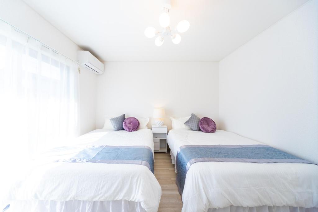two beds in a room with white walls at Miraie Yokkaichi Hazunaka in Yokkaichi