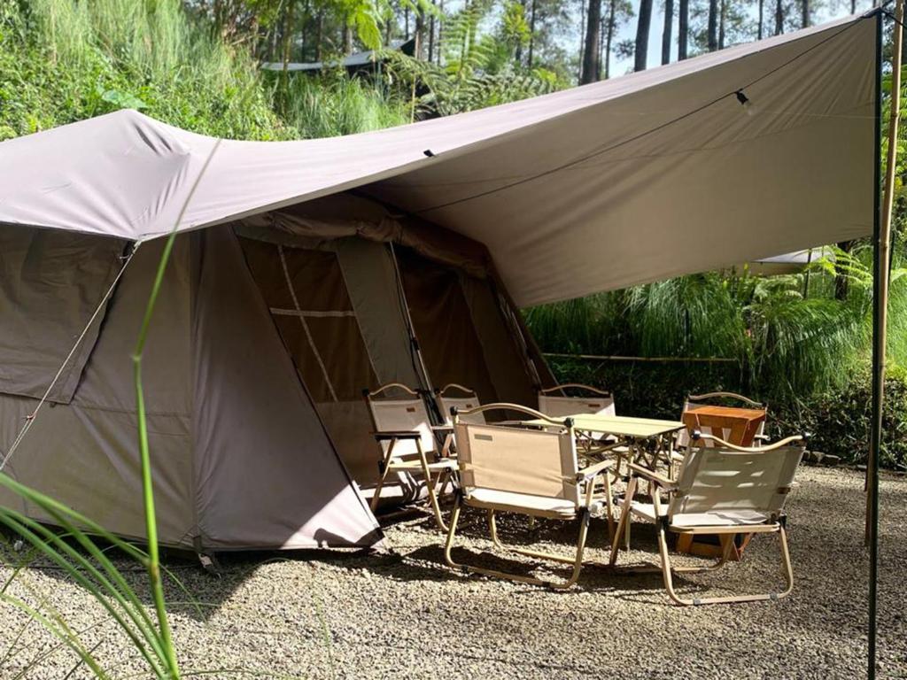 a tent with chairs and a table in front of it at corak alam glamping in Tangkubanperahu