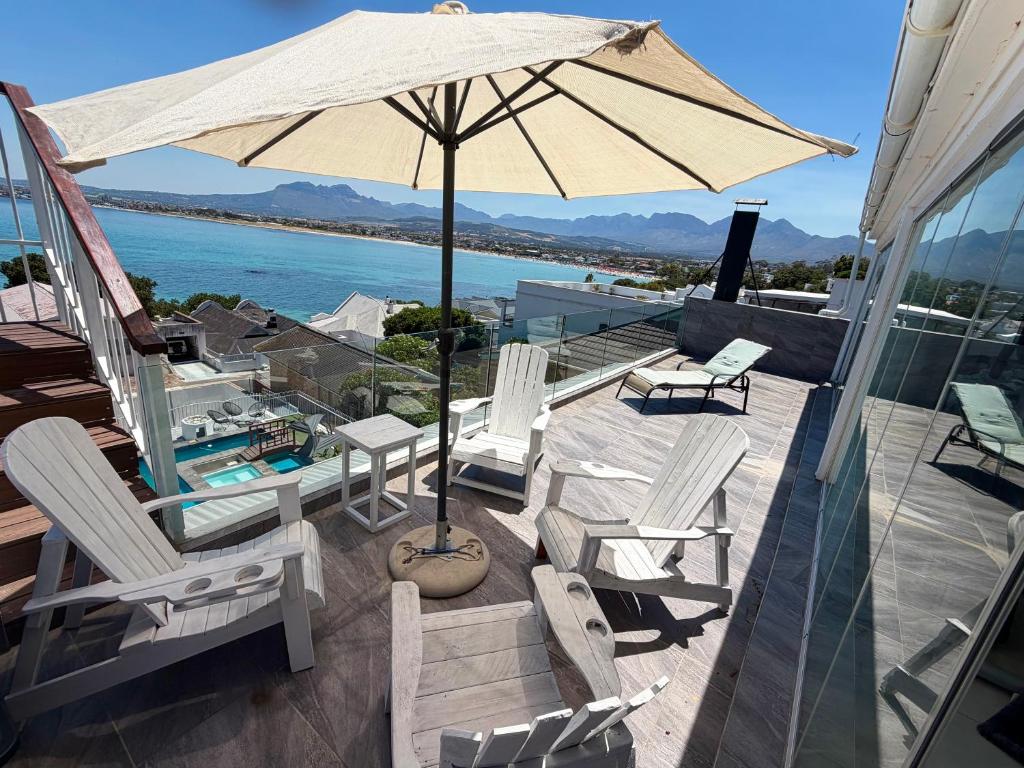 a patio with chairs and an umbrella on a house at Kiwara at C, Gordon's Bay in Gordonʼs Bay